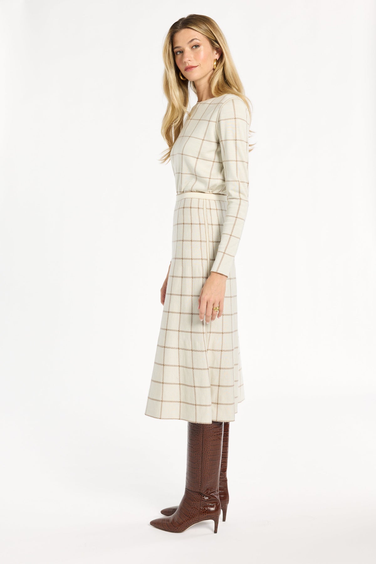 A woman modeling the cream side of the Chestnut Windowpane Plaid Reversible Flared Skirt with the matching crewneck, side view, photographed against a plain white studio background.