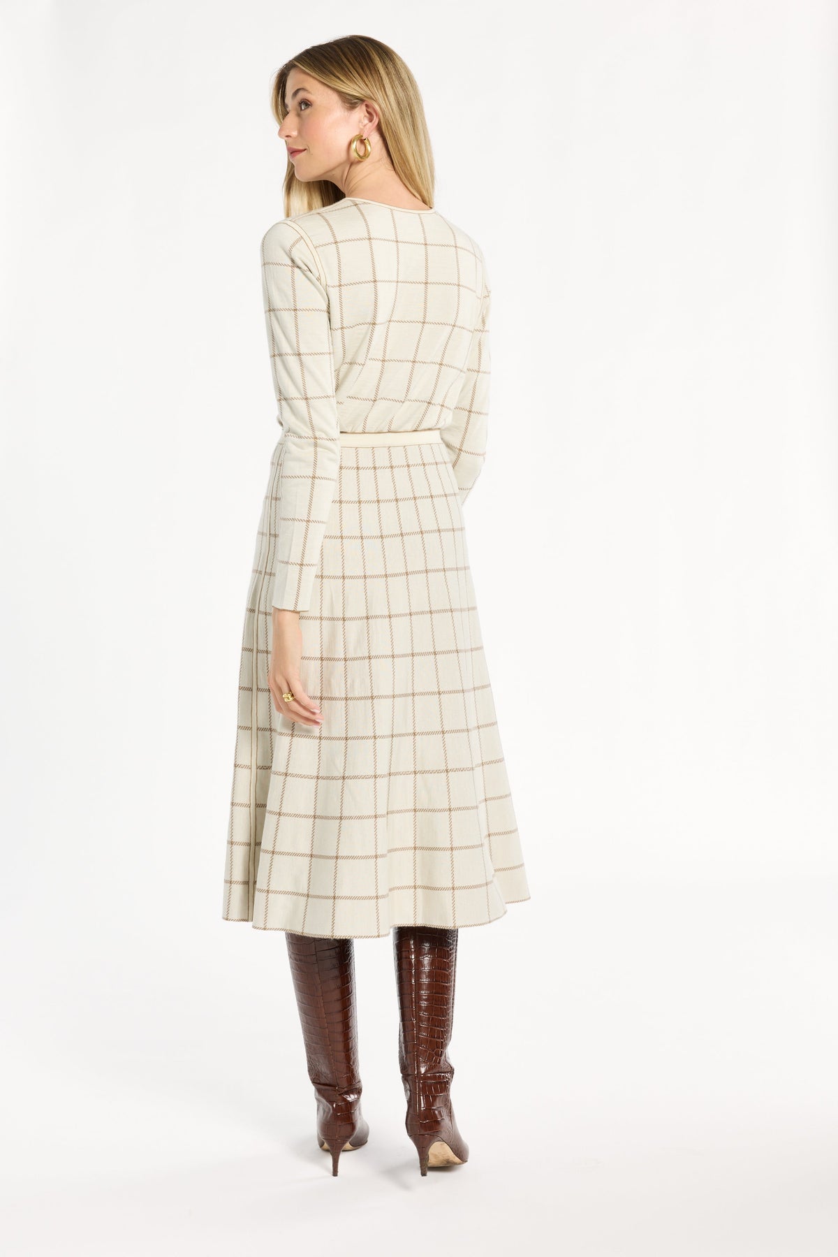 A woman modeling the cream side of the Chestnut Windowpane Plaid Reversible Flared Skirt with the matching crewneck, back view, photographed against a plain white studio background.
