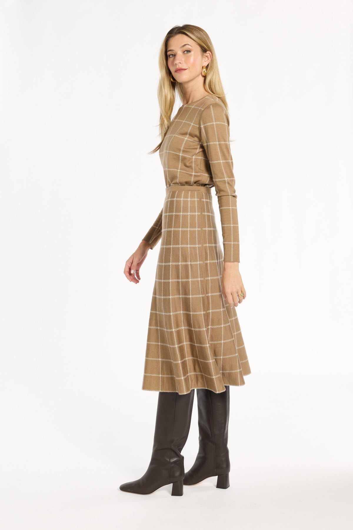 A woman modeling the chestnut side of the Windowpane Plaid Reversible Flared Skirt with the matching crewneck, side view, photographed against a plain white studio background.