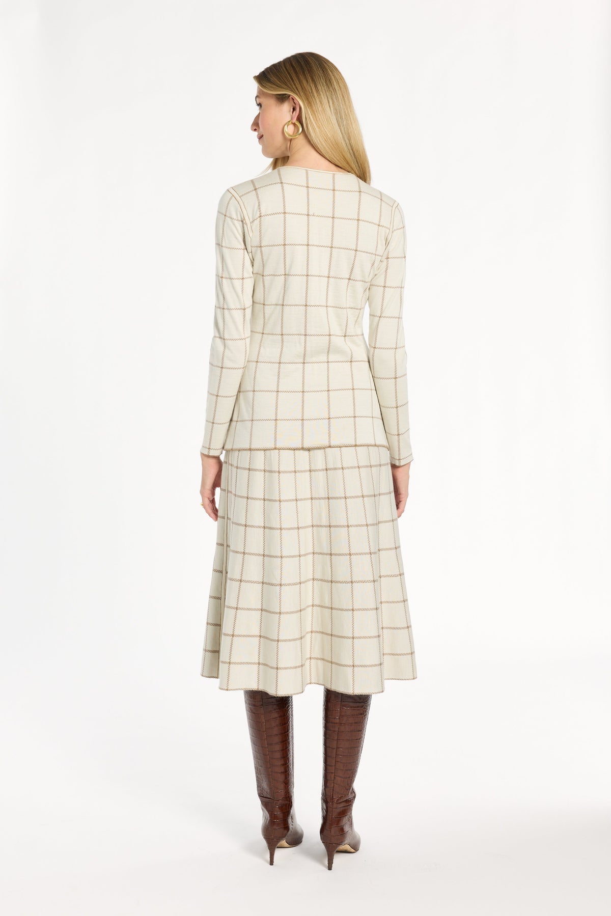 A woman modeling the cream side of the Reversible Knit Jacket with the matching windowpane skirt, back view, photographed against a plain white studio background.