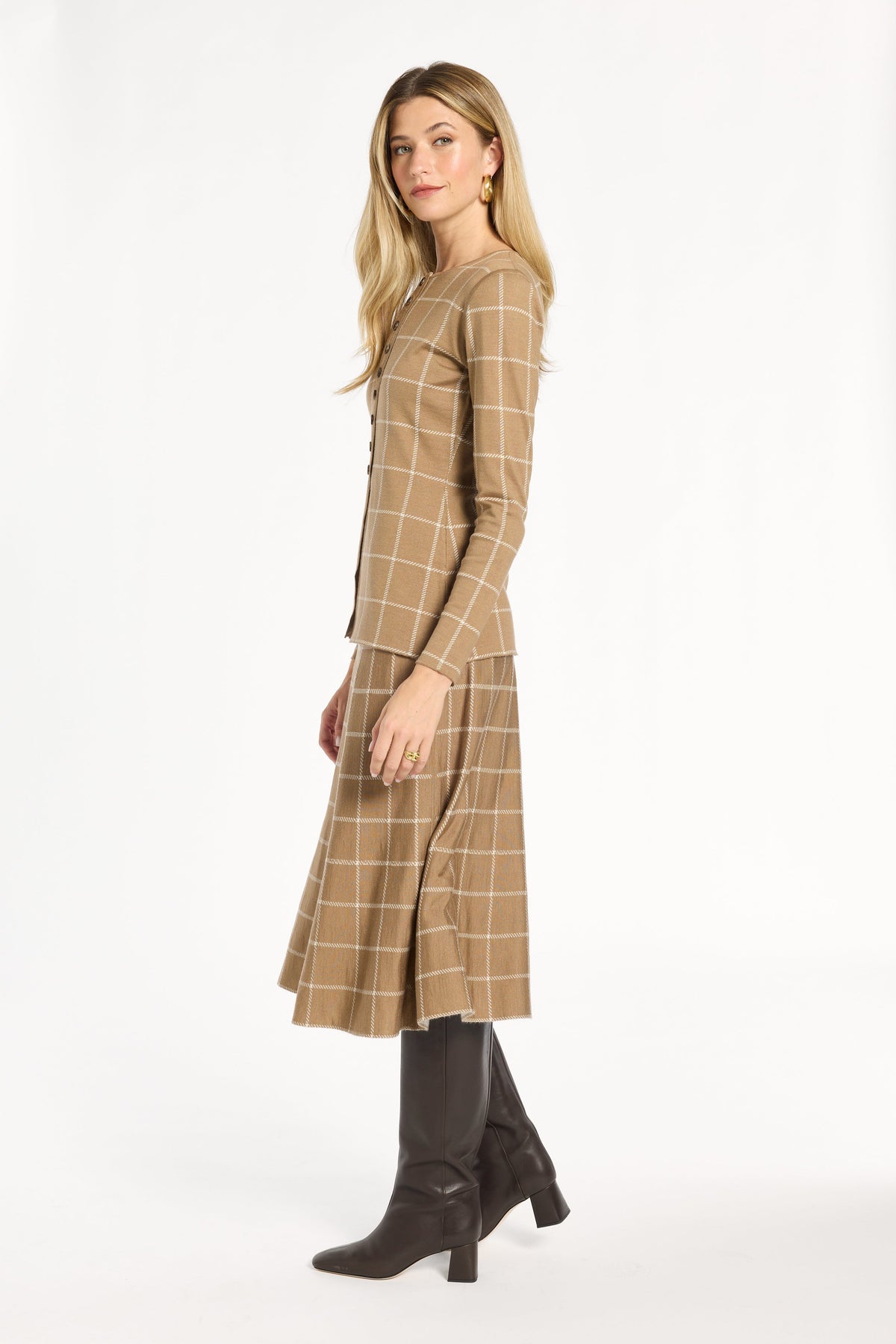 A woman modeling the chestnut side of the Windowpane Plaid Reversible Knit Jacket with the matching skirt, side view, photographed against a plain white studio background.