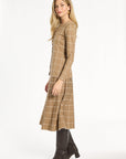 A woman modeling the chestnut side of the Windowpane Plaid Reversible Knit Jacket with the matching skirt, side view, photographed against a plain white studio background.