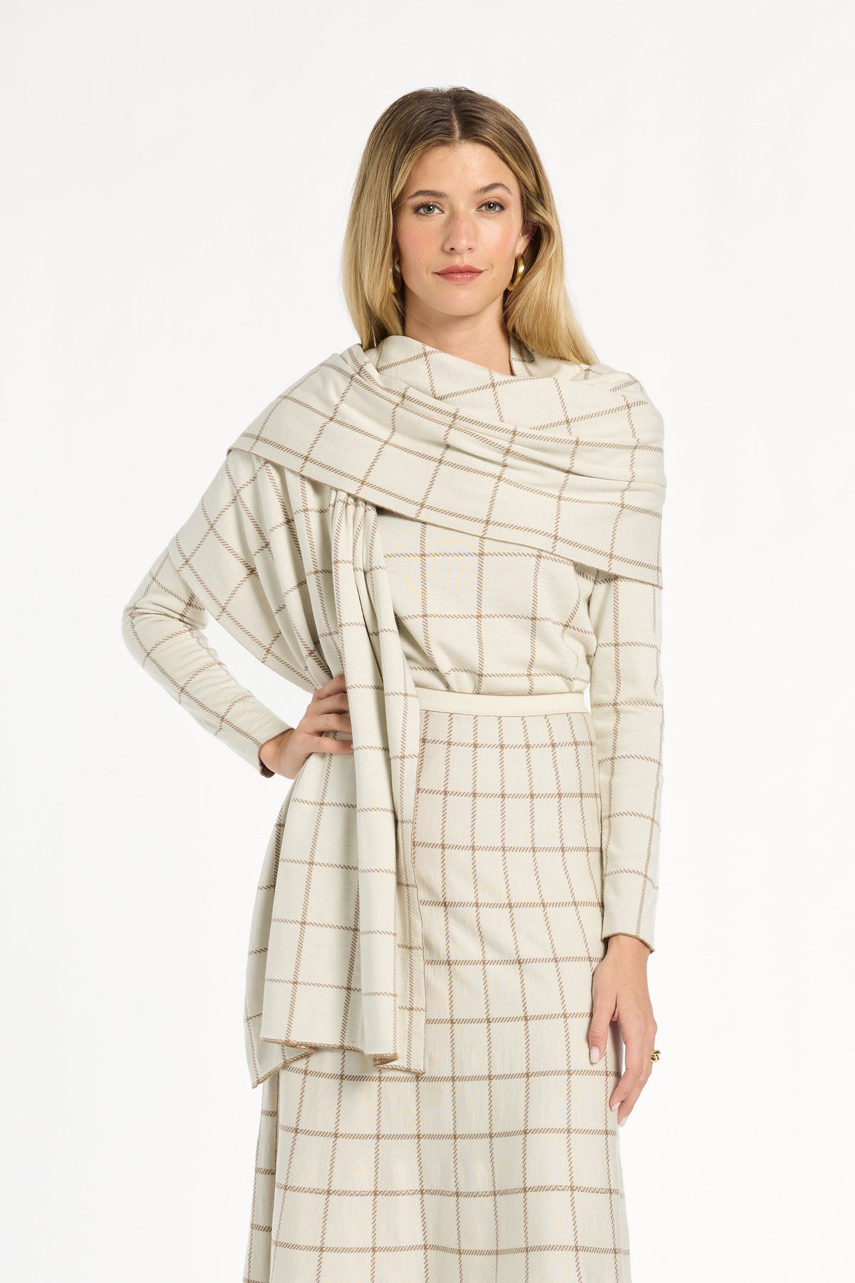 A woman modeling the cream side of the Chestnut Windowpane Plaid Reversible Wrap draped over the matching skirt and crewneck, front view, photographed against a plain white studio background.