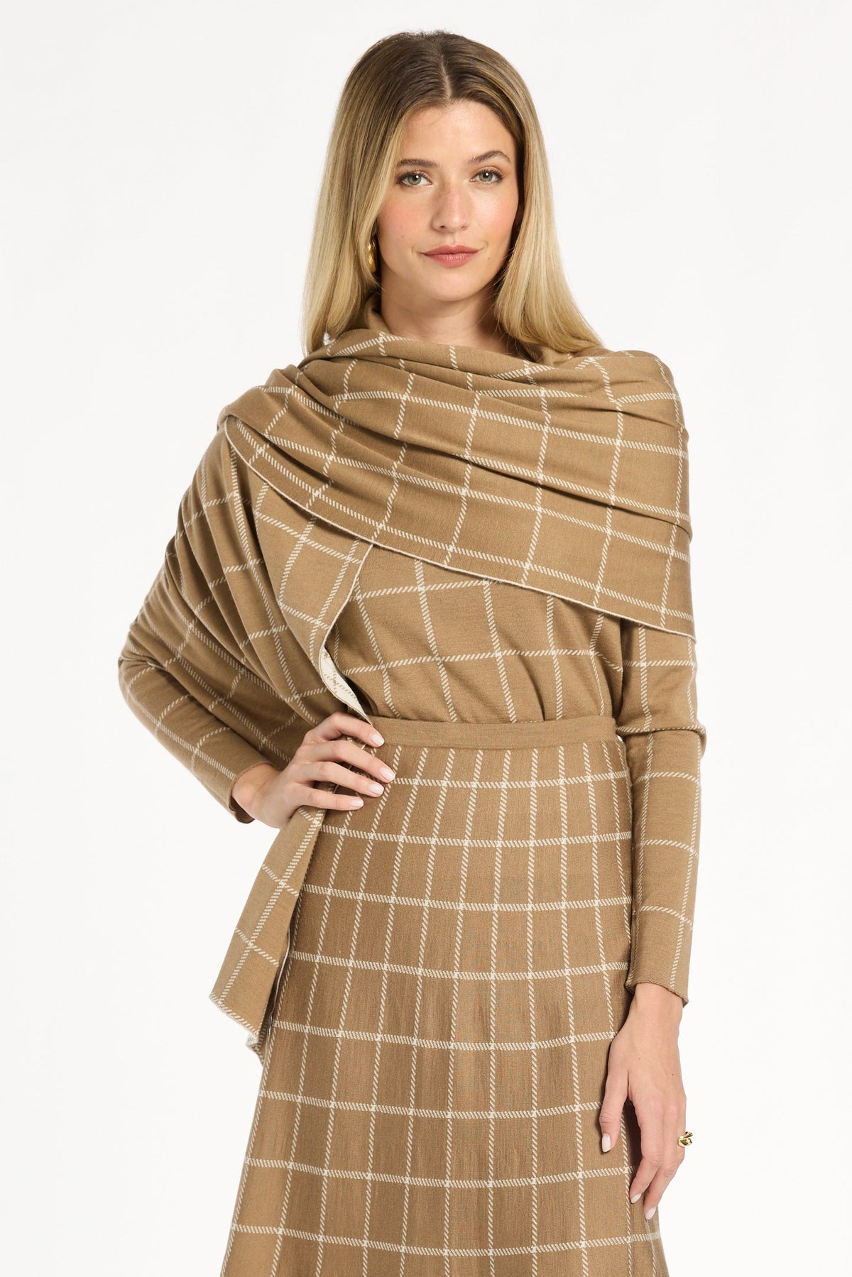 A woman modeling the chestnut side of the Windowpane Plaid Reversible Wrap draped over the matching skirt and crewneck, front view, photographed against a plain white studio background.