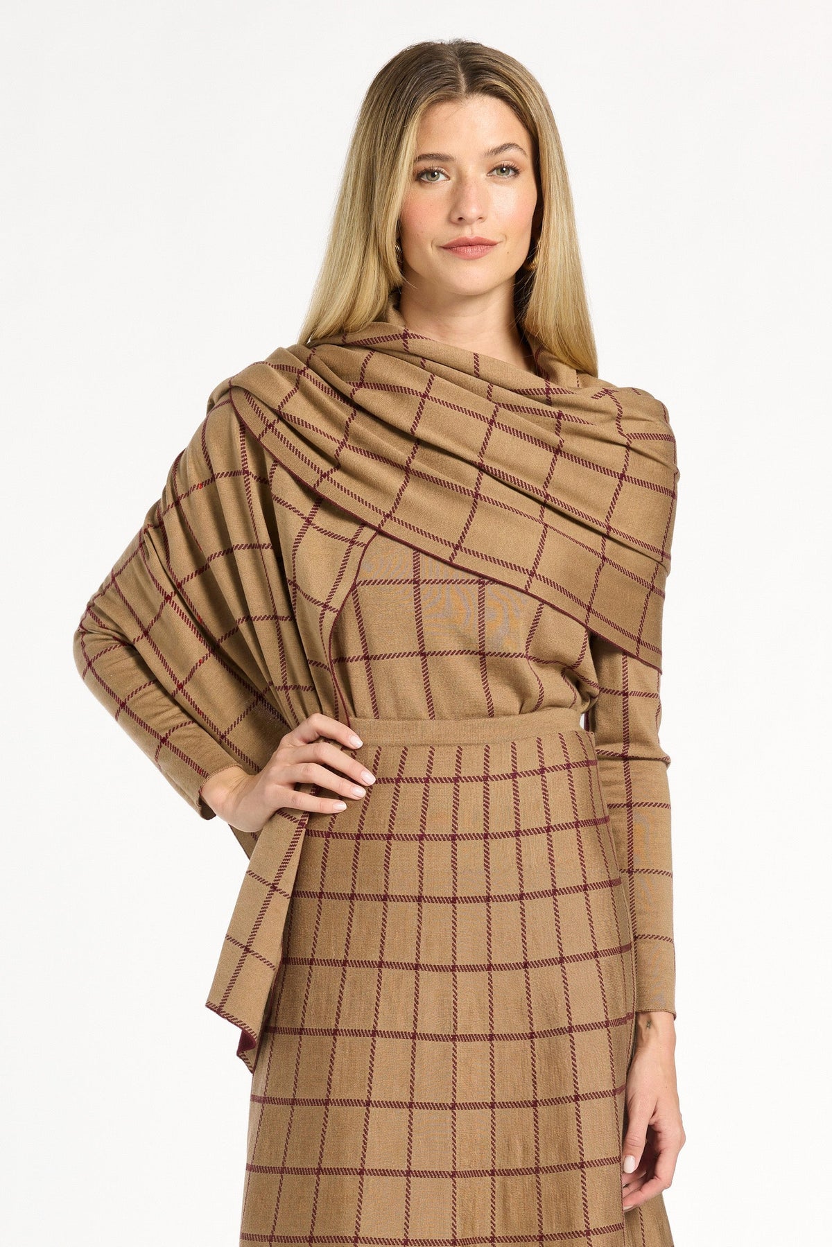 A woman modeling the chestnut reverse of the Cranberry Windowpane Plaid Wrap draped over the matching skirt and crewneck, front view, photographed against a plain white studio background.
