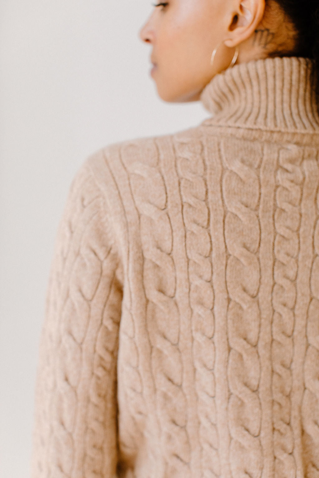 Close up of model wearing the Camel Cable-Knit Turtleneck sweater showcasing the sweater's quality design and comfortable texture.