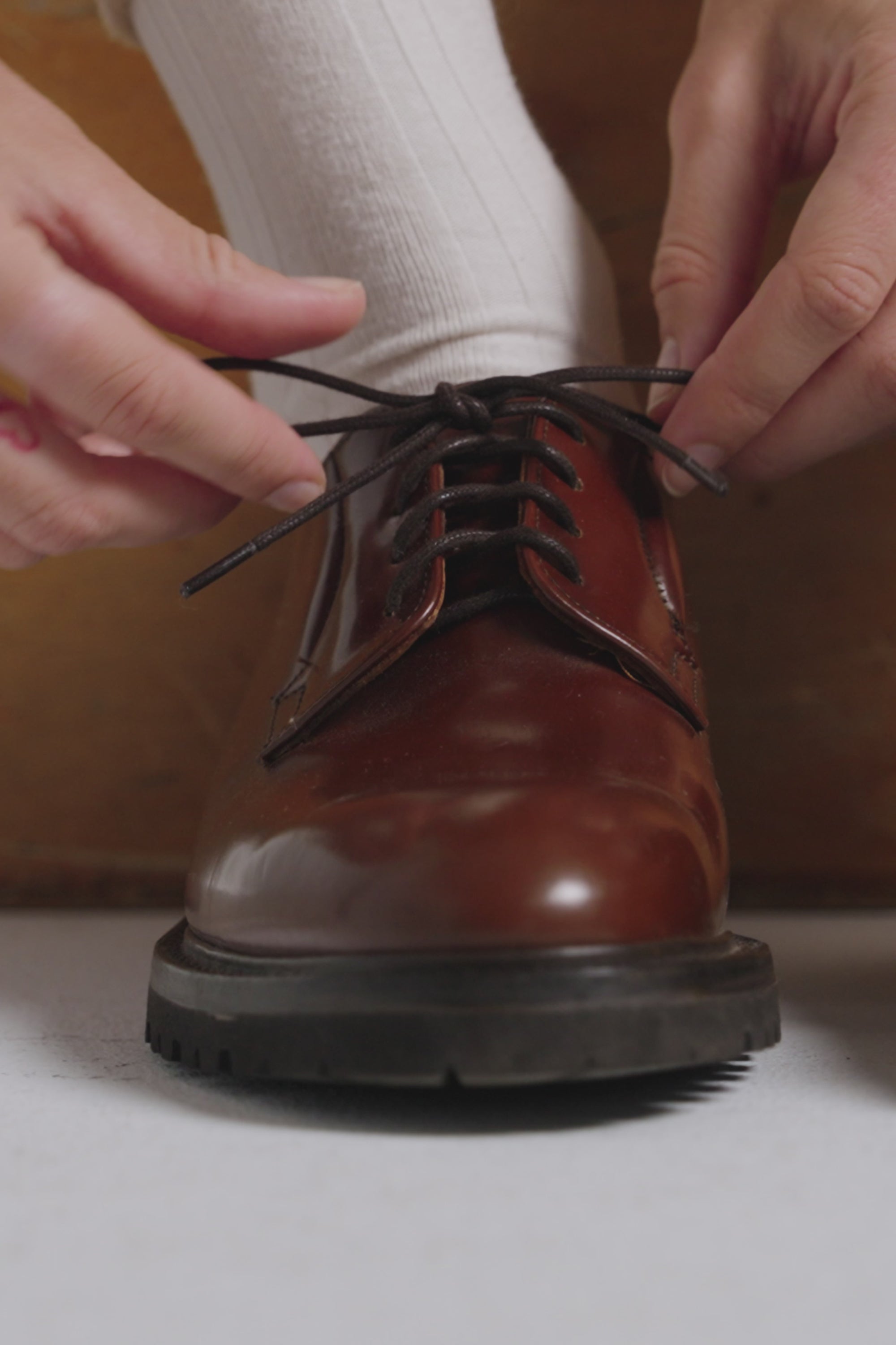 Woman tying a the shoe laces on a hazelnut derby shoe