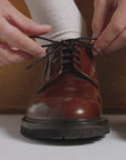 Woman tying a the shoe laces on a hazelnut derby shoe