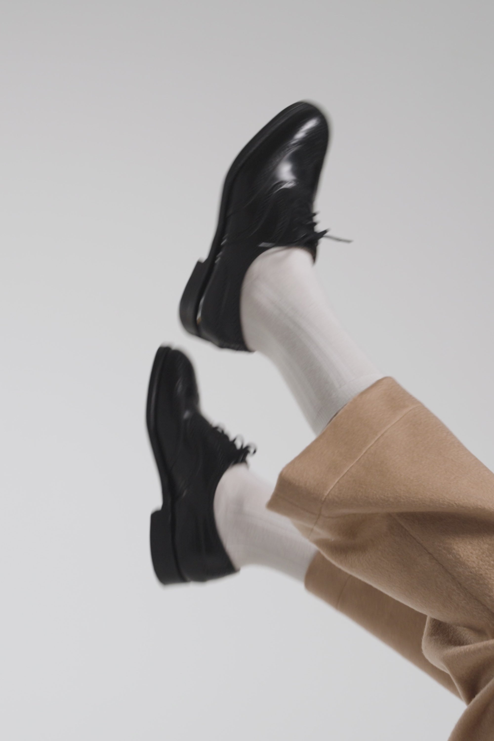 Woman waving her shoes in the air on a white backdrop
