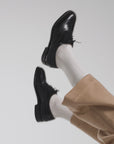 Woman waving her shoes in the air on a white backdrop