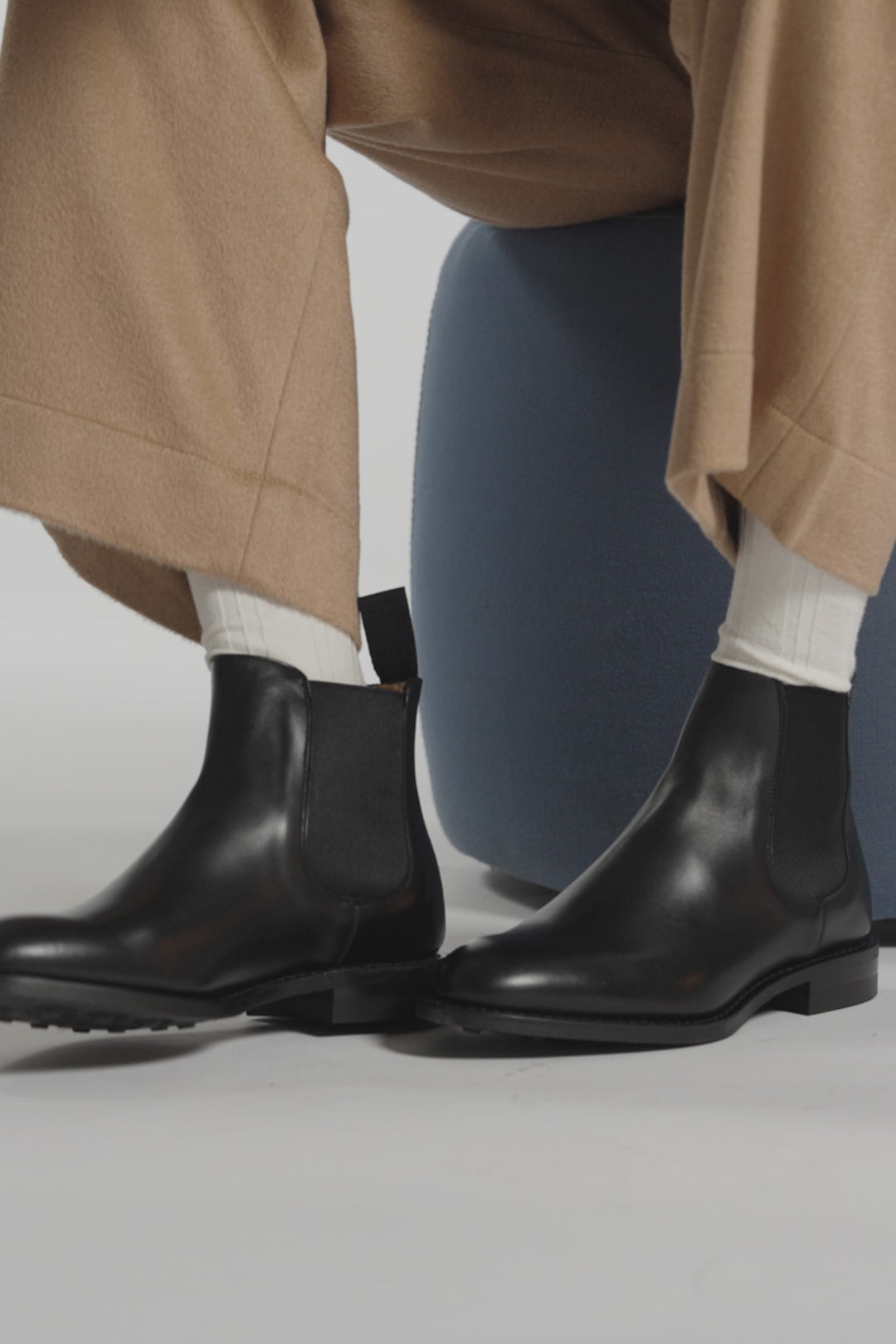 Black Italian made boots tapping on a white studio ground and backdrop