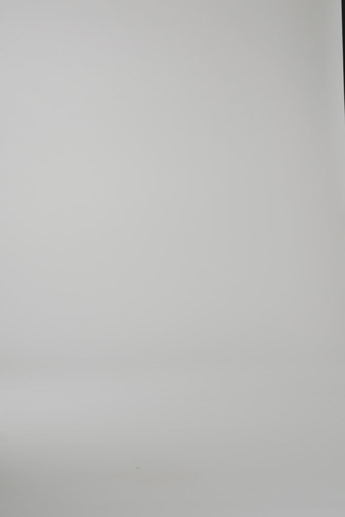 A woman modeling a red cashmere wrap on a light gray studio backdrop