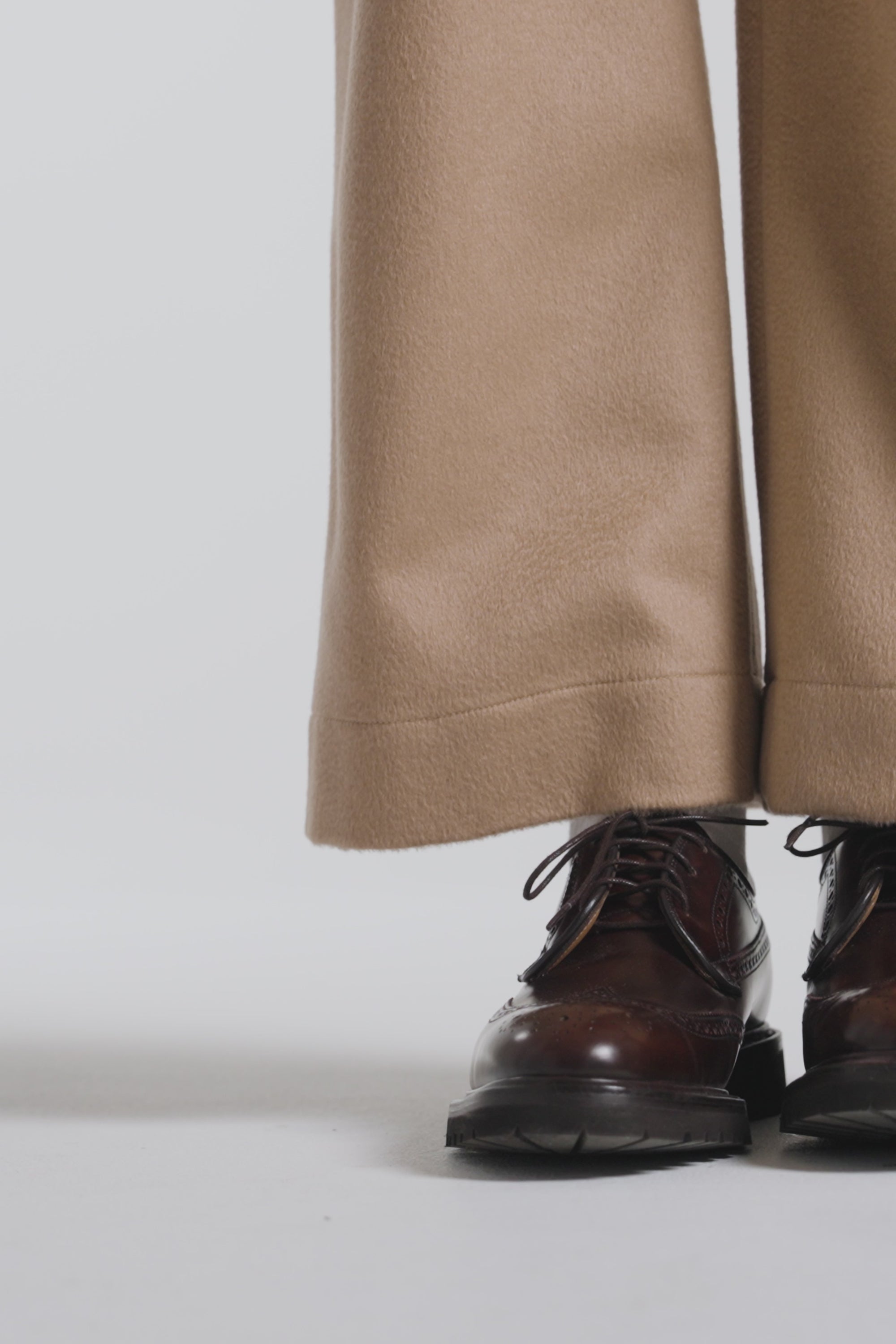 Woman modeling a dark brown pair derby shoes on a white backdrop