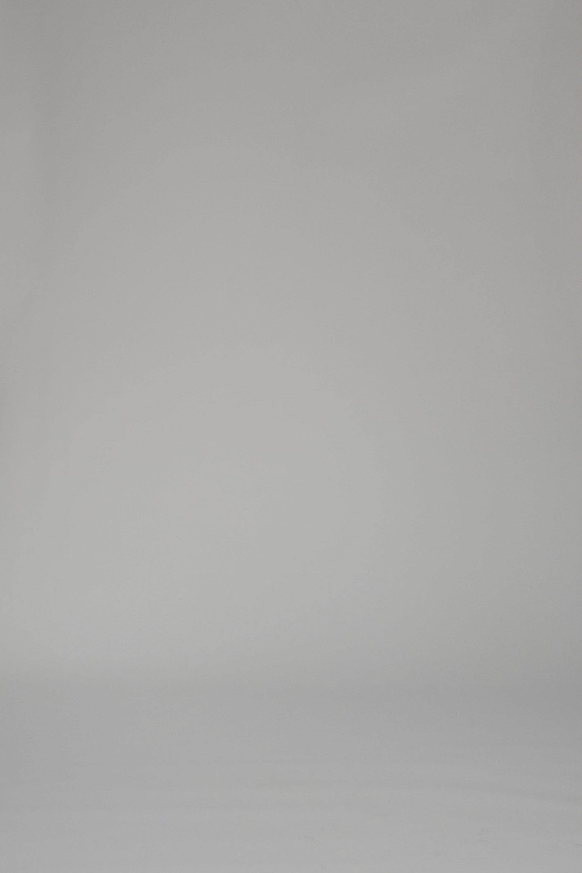 Woman modeling a mid-length white dress with a floral pattern on a plain backdrop