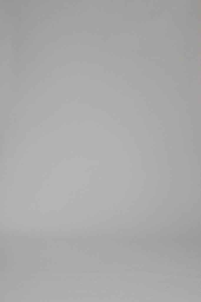 Woman modeling a mid-length white dress with a floral pattern on a plain backdrop