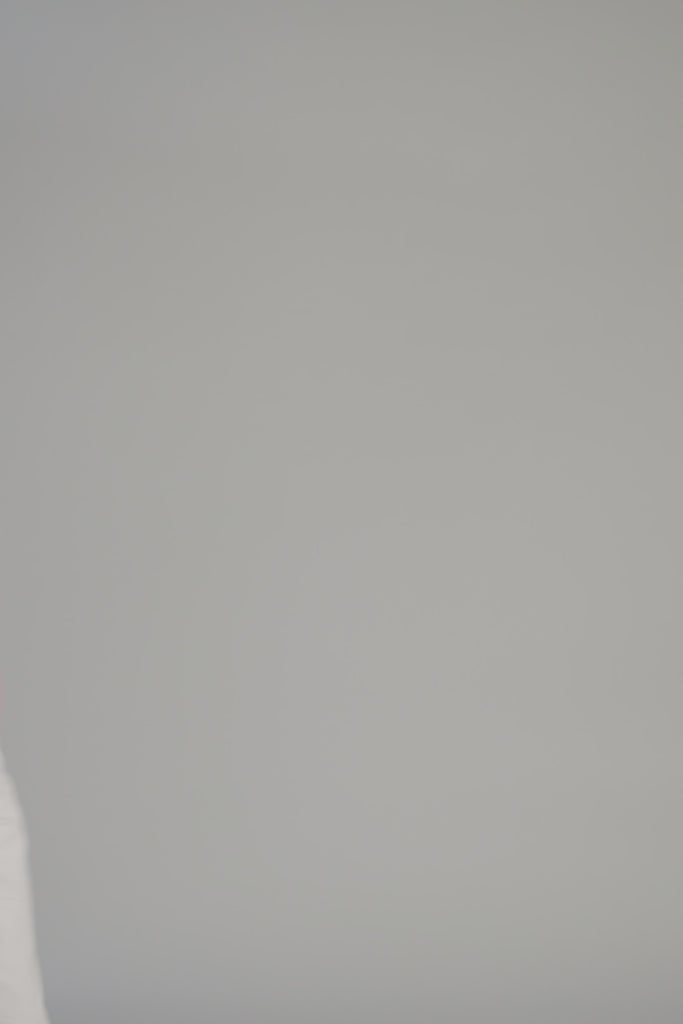 woman wearing a pink sweater with graphic on it on a white backdrop