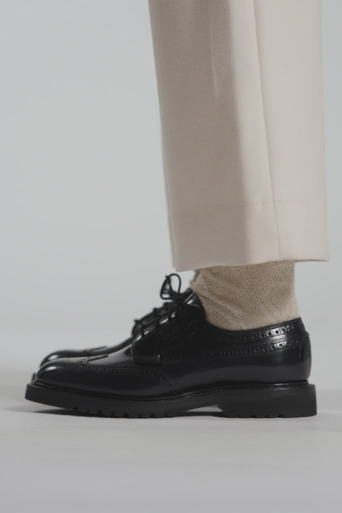 Close up video of navy shoes and cream pants on a white background