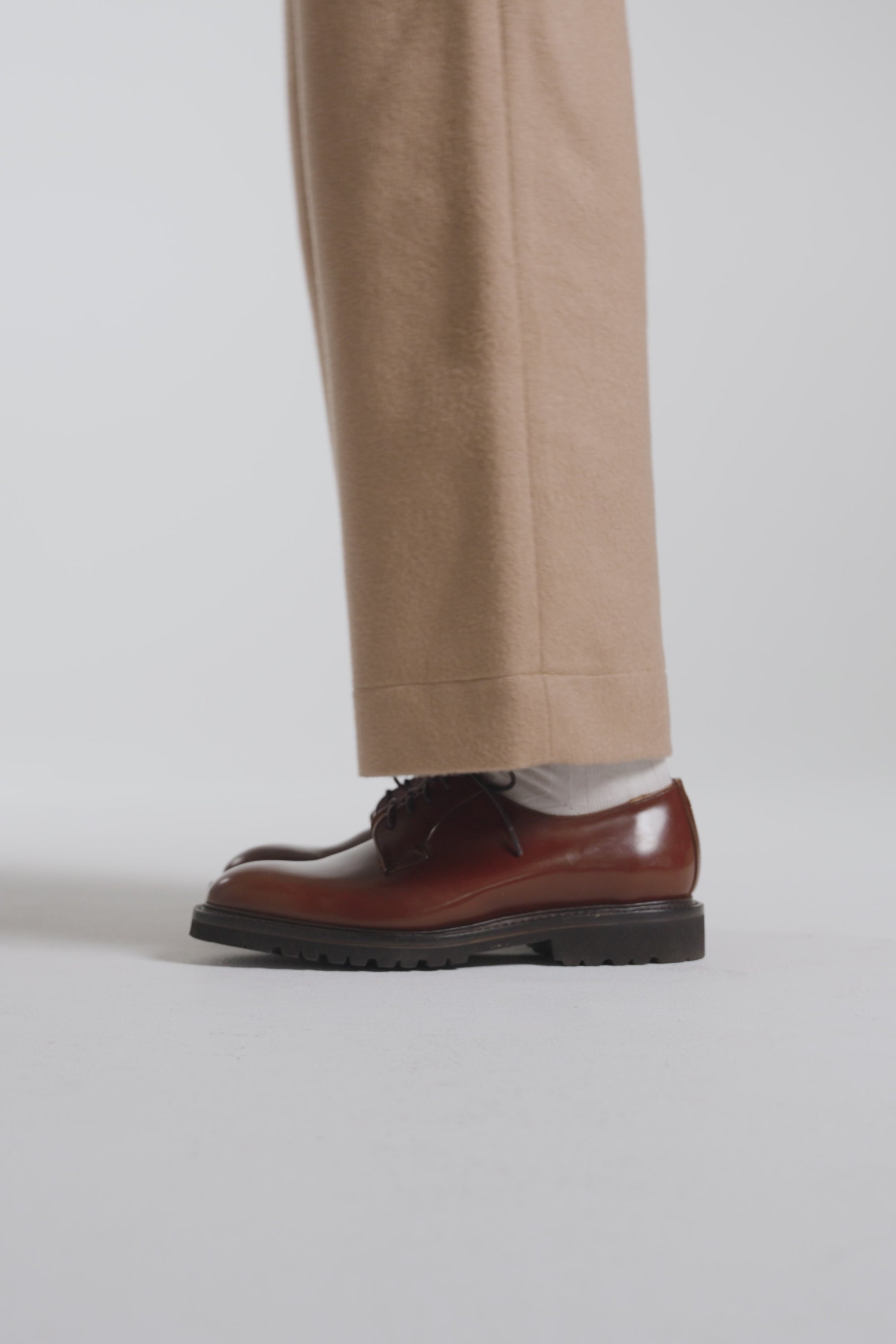 Woman modeling hazelnut derby shoes on a white backdrop