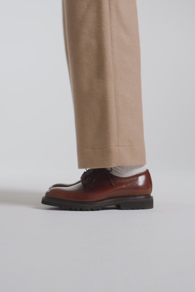 Woman modeling hazelnut derby shoes on a white backdrop