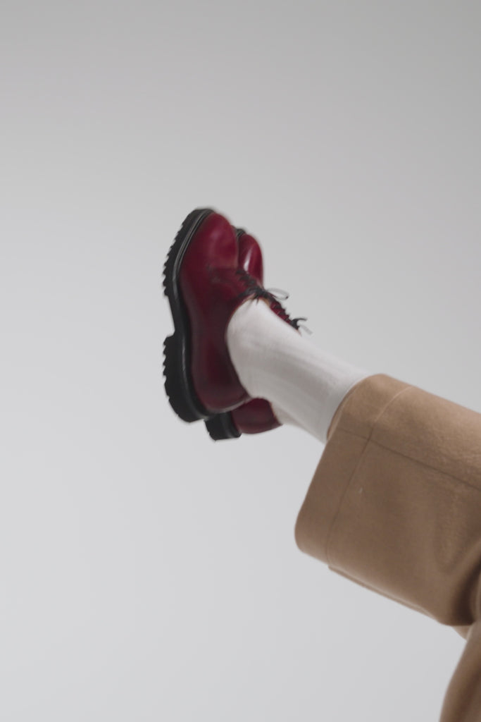 Woman modeling European shoes with tan  pants on a white backdrop