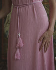 A video of a woman modeling a pleated silk dress on a patterned backdrop