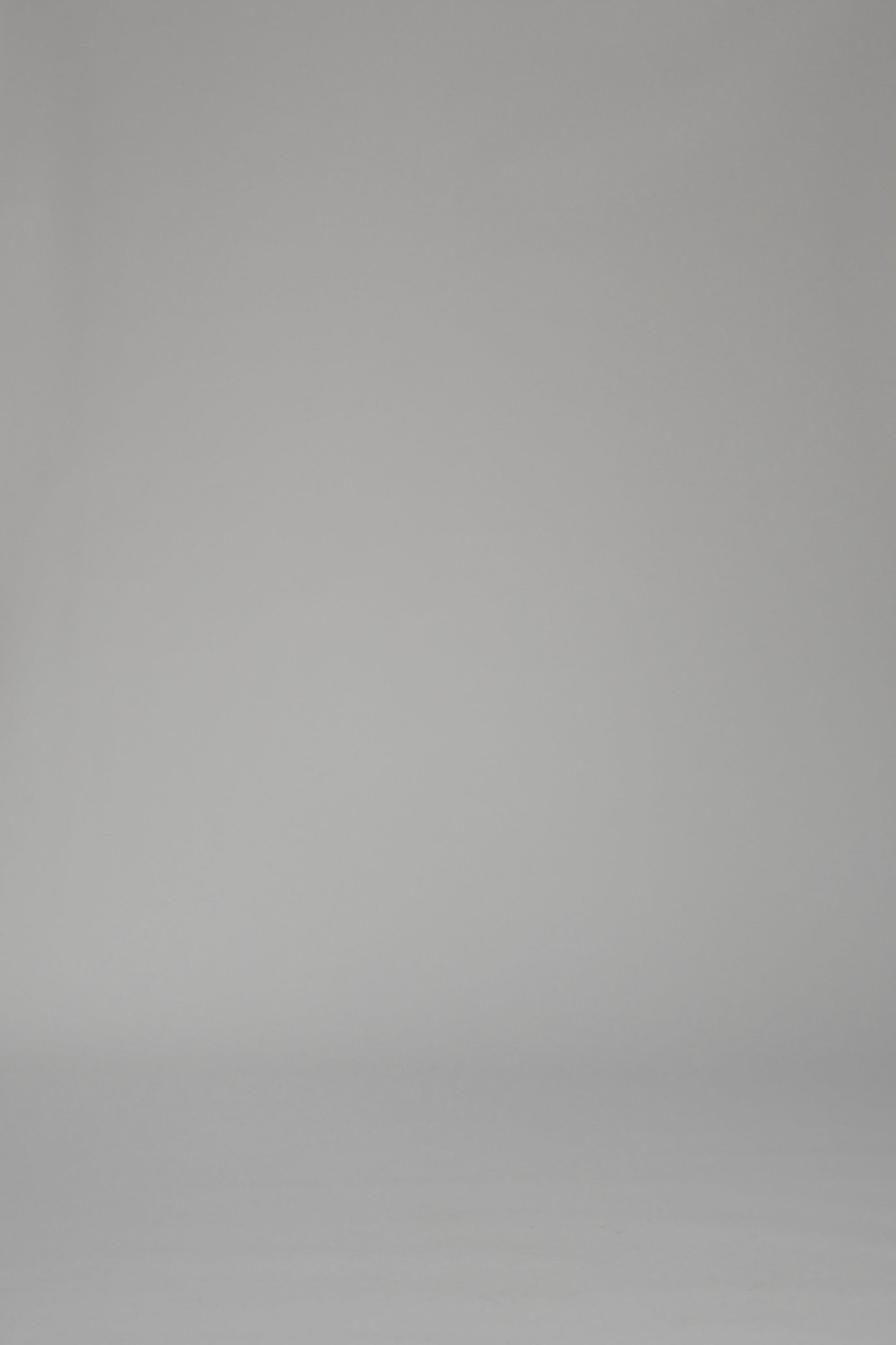 Woman modeling a mid-length green striped dress with oranges on a white backdrop