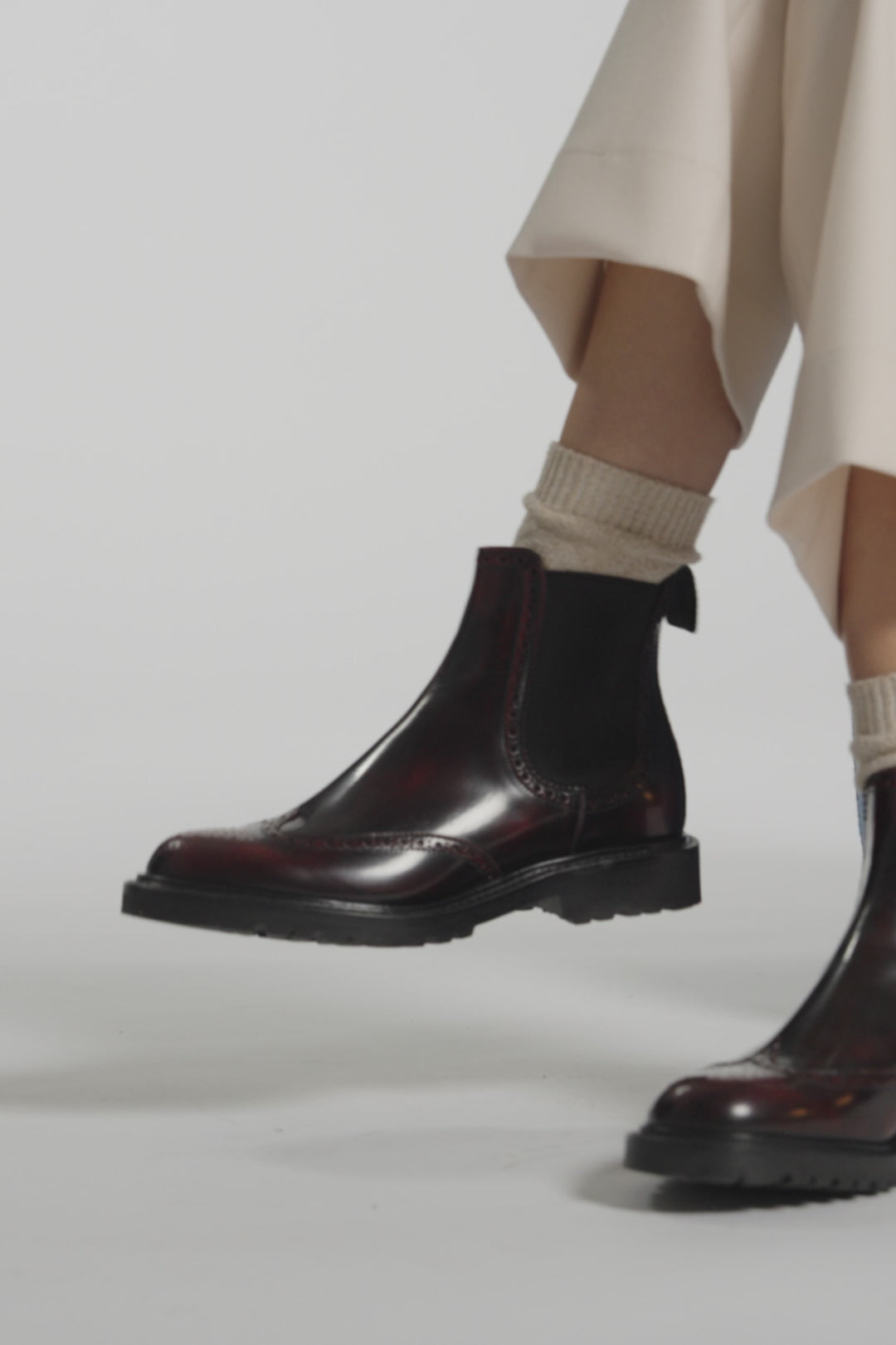 Close up video of burgundy boots on a white background
