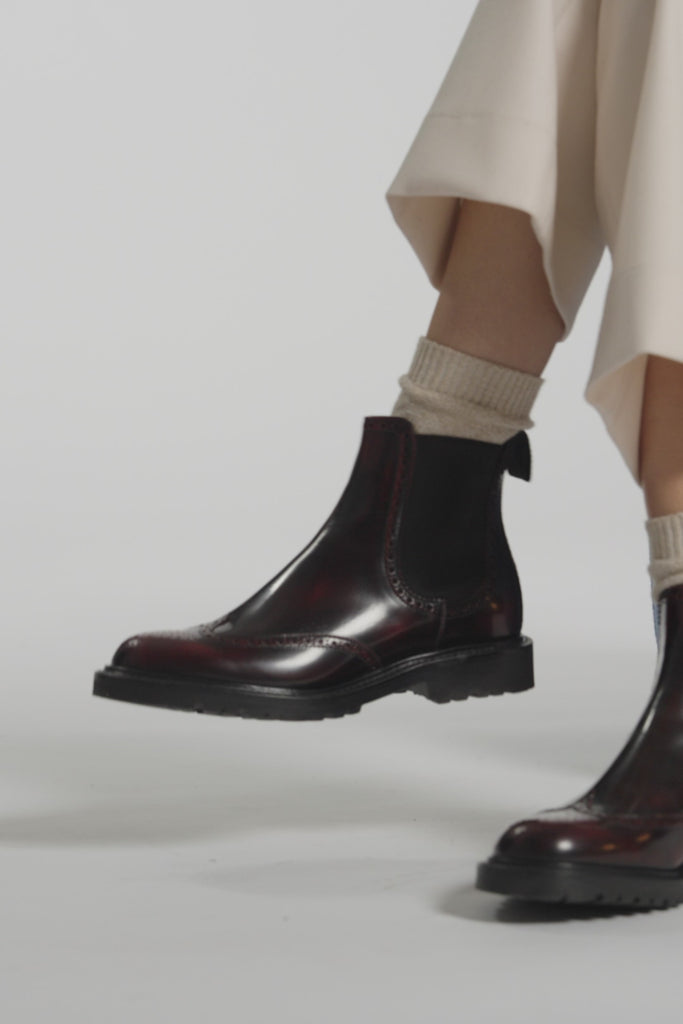 Close up video of burgundy boots on a white background