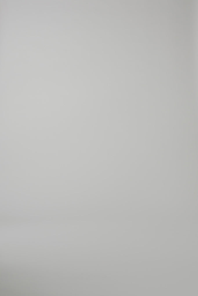 A woman modeling a knee length white floral dress on a light backdrop