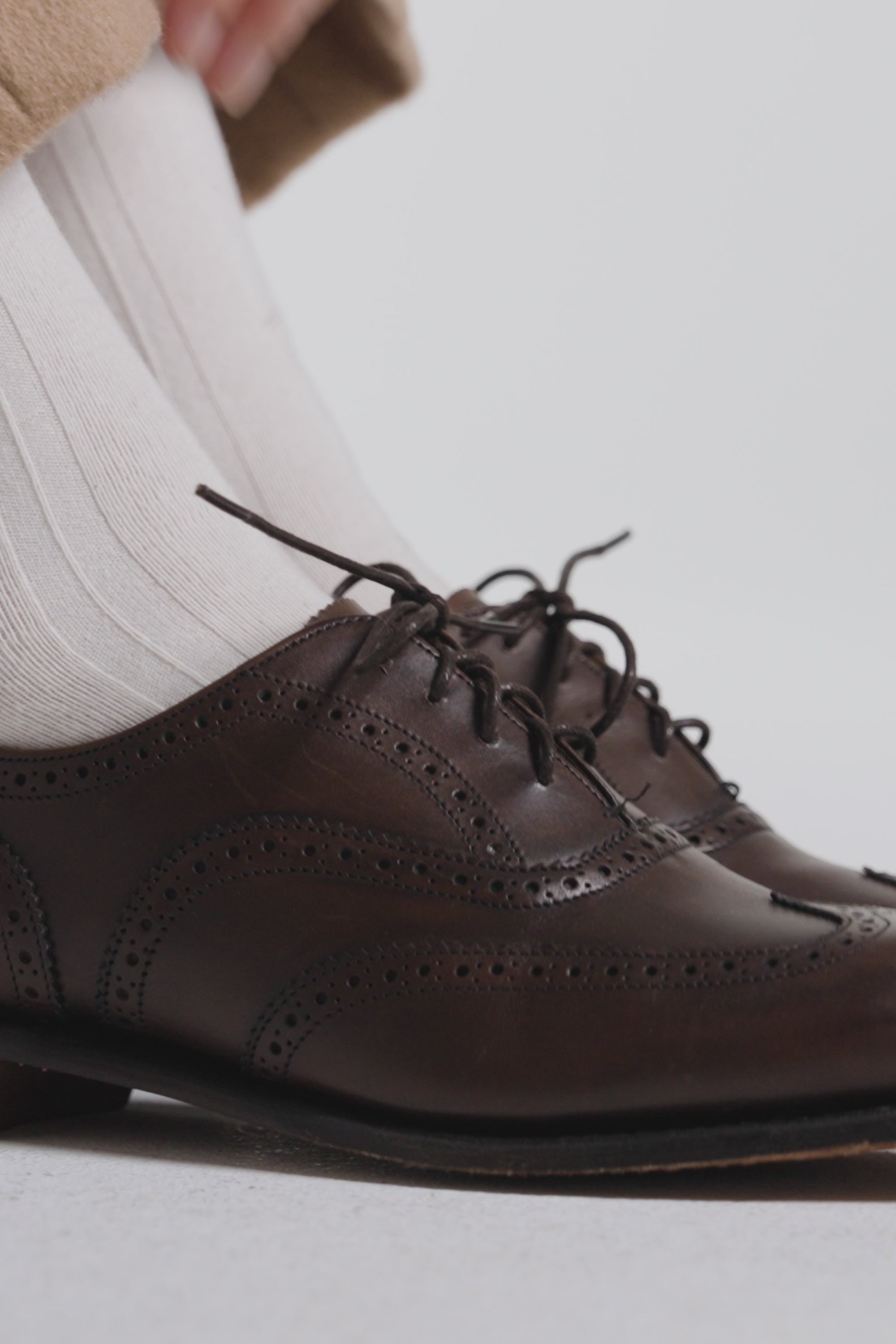 Close up of brown oxford shoes with white socks on a white background