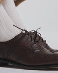Close up of brown oxford shoes with white socks on a white background