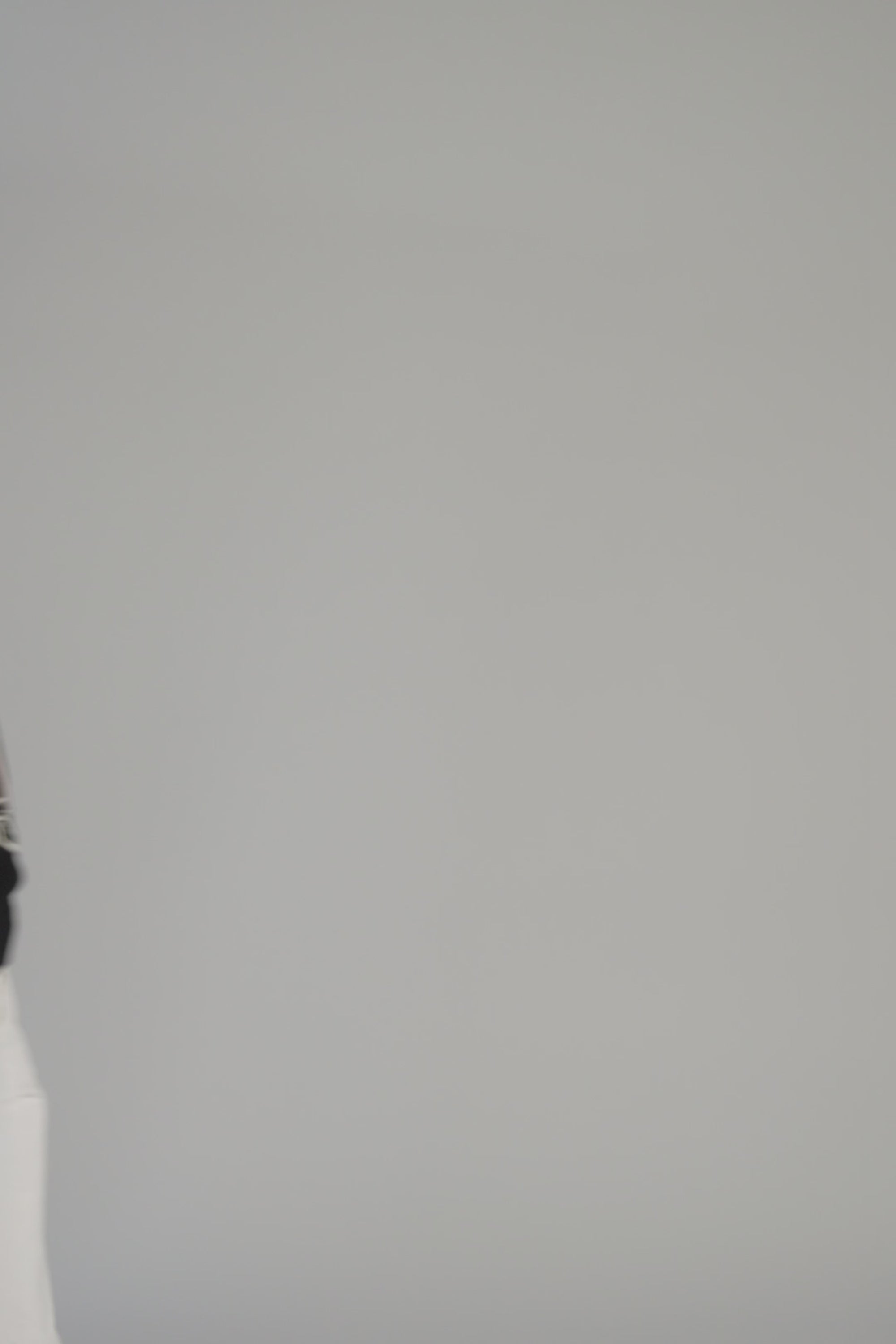 Woman wearing a black sweater with an ostrich dancing on a gray backdrop 