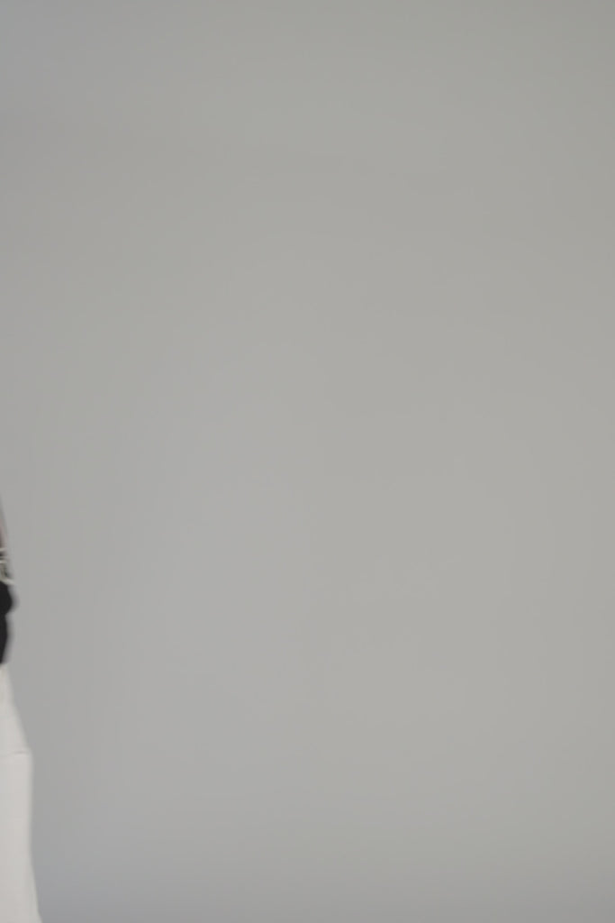Woman wearing a black sweater with an ostrich dancing on a gray backdrop 