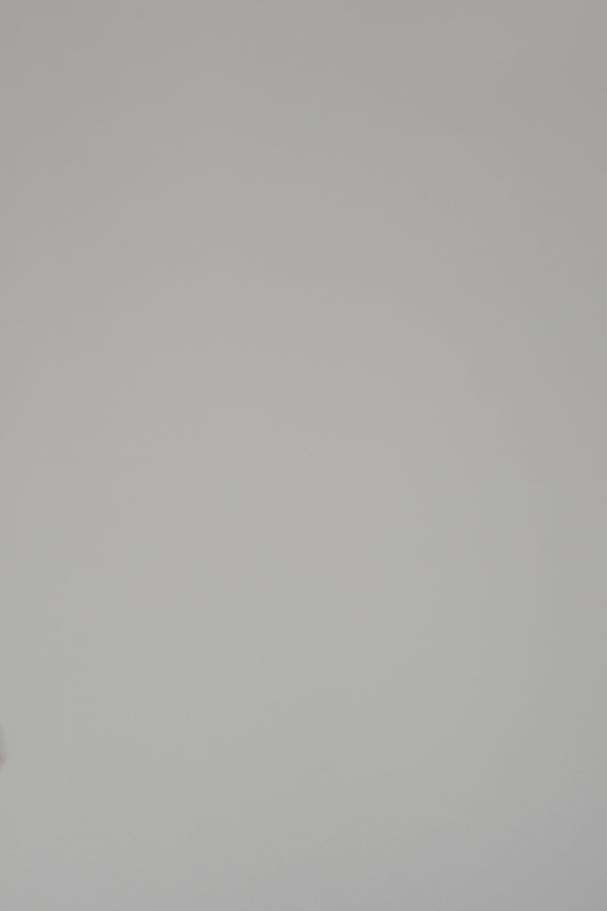 Woman modeling a long sleeve sweater on a plain backdrop