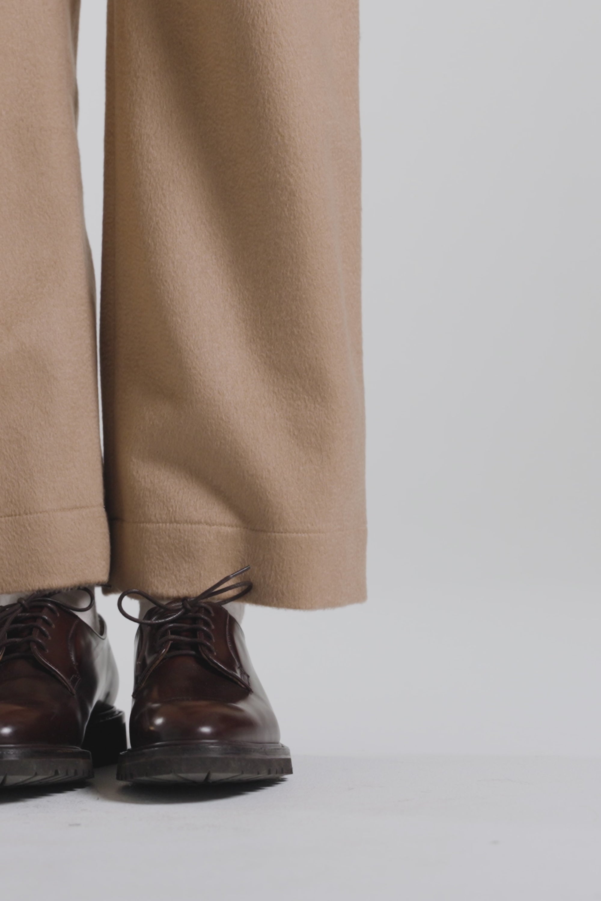 Model wearing tan pants and dark brown derby shoes on a white backdrop
