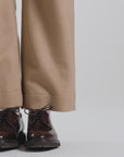 Model wearing tan pants and dark brown derby shoes on a white backdrop