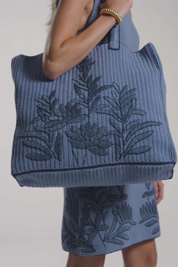 A woman modeling a hand-crochet tote bag on a white background