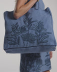 A woman modeling a hand-crochet tote bag on a white background