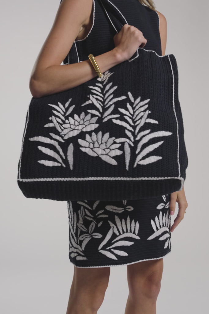 Woman modeling a black hand-crochet tote bag on a white backdrop