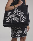 Woman modeling a black hand-crochet tote bag on a white backdrop