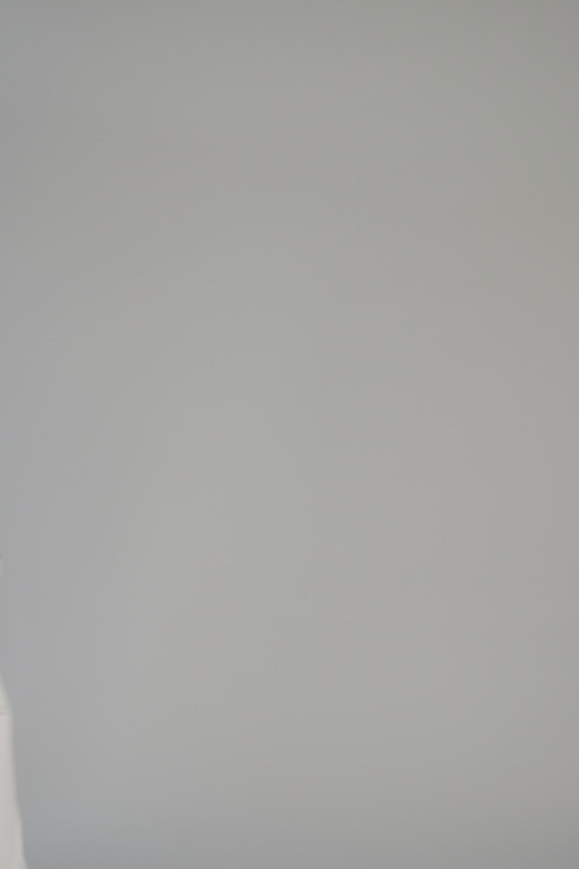 Woman modeling a cream sweater that has a giraffe on a bike on a gray backdrop