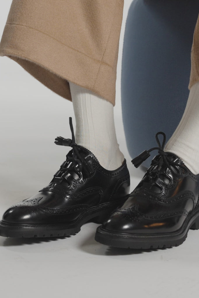 Close up of black shoes with white ankle socks on a white background