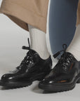Close up of black shoes with white ankle socks on a white background