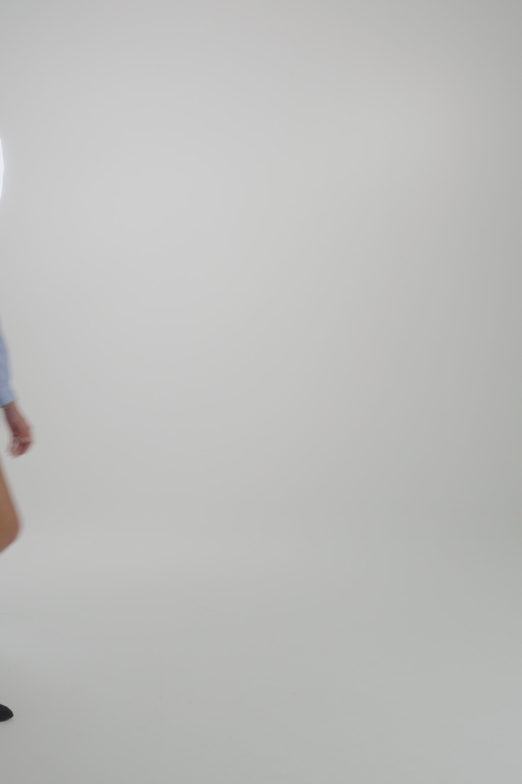 Woman wearing a light blue blouse with the matching shorts on a plain backdrop