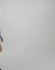Woman wearing a light blue blouse with the matching shorts on a plain backdrop