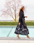 Woman wearing a black maxi dress with floral patterns outside on patio