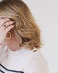 Close-up of EL wearing the Perfect Striped Crewneck in cream with navy mariner stripes, highlighting the handcrafted Italian gold buttons.